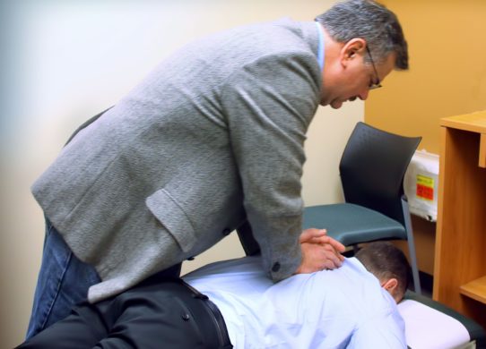 chiropractic doctor in therapy session with his patient